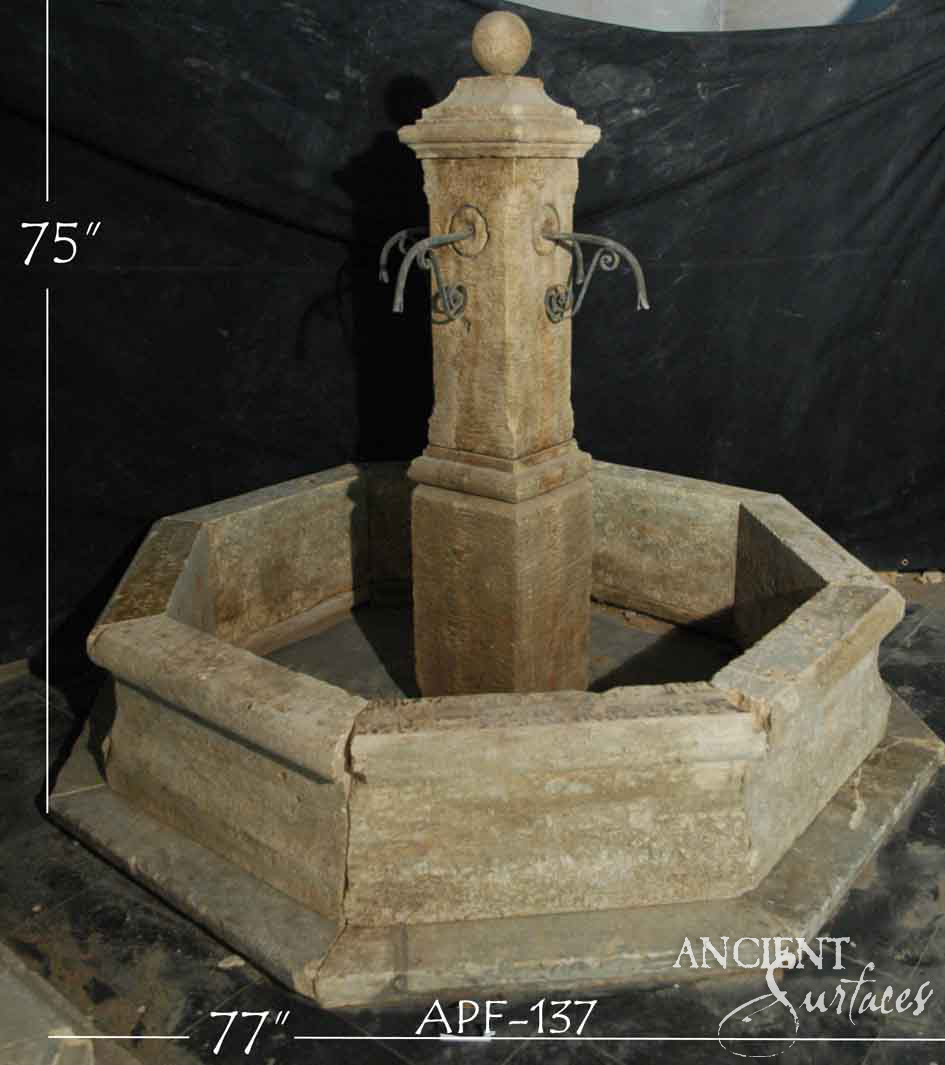 Honey-toned reclaimed limestone pool fountain with iron scroll spouts and an octagonal basin