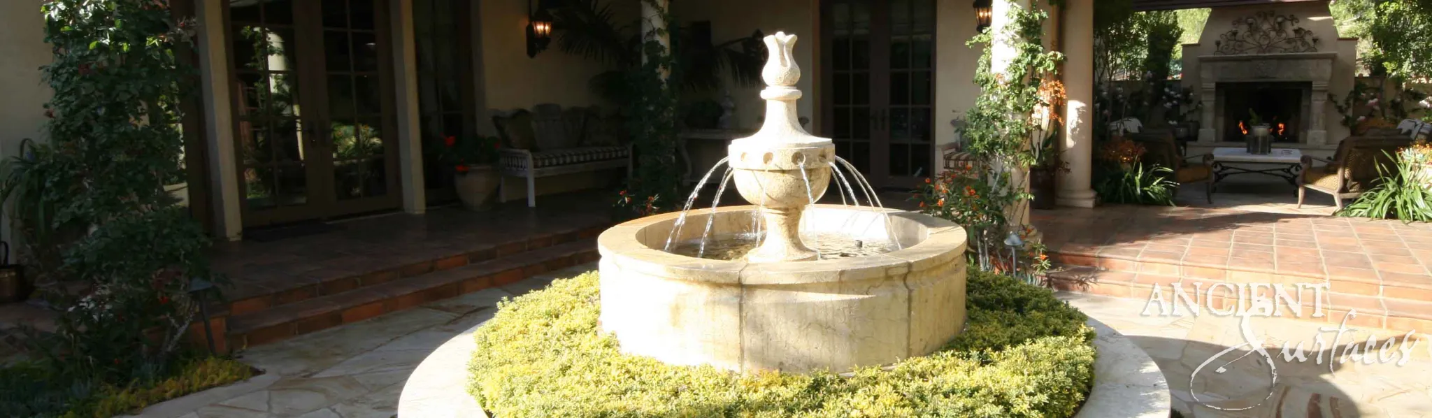 Reclaimed limestone pool fountain with an ornate urn finial and flowing water jets in a Mediterranean courtyard