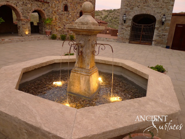 Illuminated reclaimed limestone courtyard fountain with flowing water at dusk