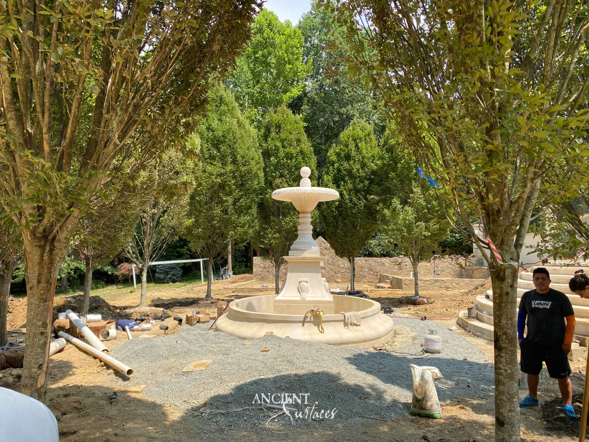 Two-tier urn reclaimed limestone pool fountain on a fluted plinth in an estate garden